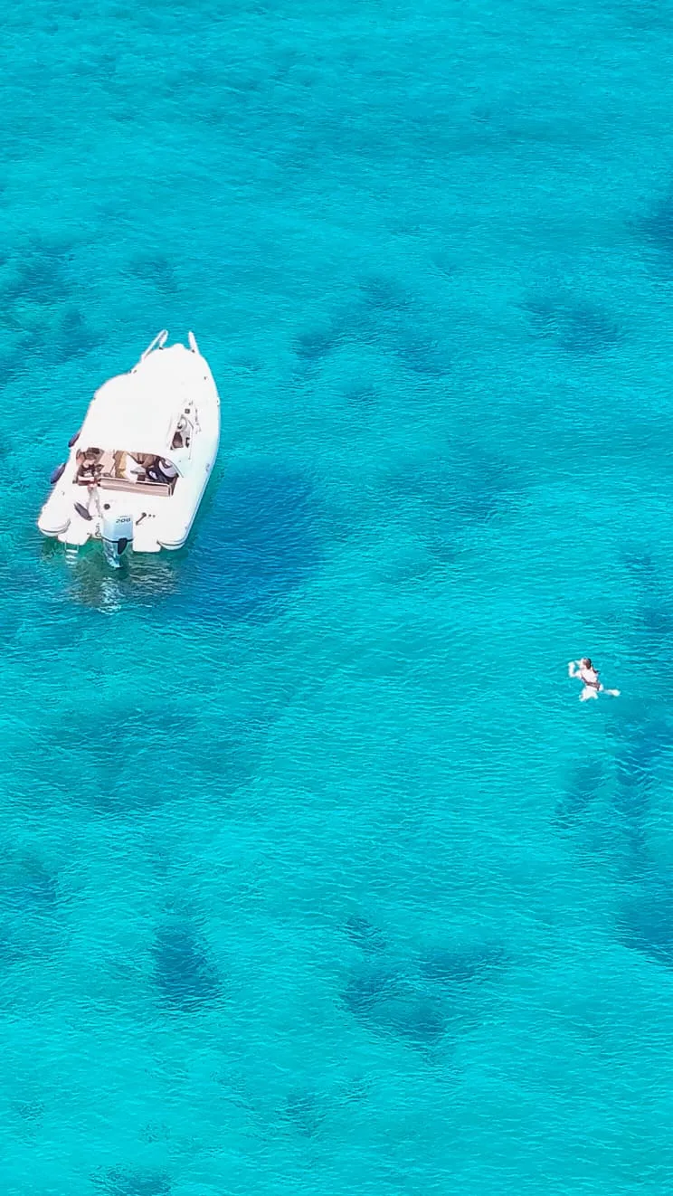 Boat and swimmer in crystal-clear water
